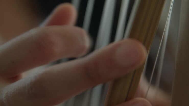 Primo piano estremamente ravvicinato delle mani di una ragazza che suonano l'arpa africana Kora a corde percussive, riprese ravvicinate