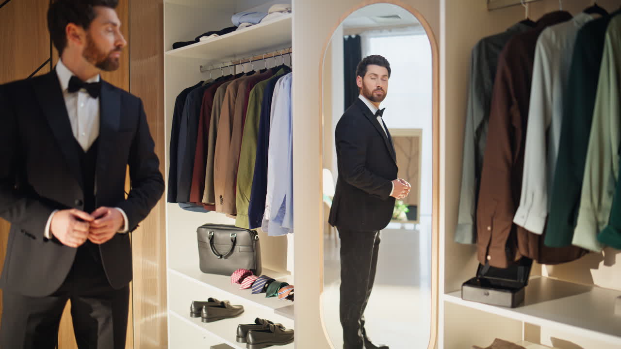 Cavalheiro confiante ajeitando o visual, preparando um terno elegante no closet.