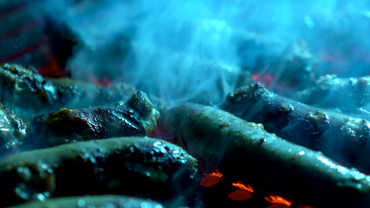 붉은 불이 붙은 뜨거운 그릴에서 땀을 흘리는 소시지 흡연