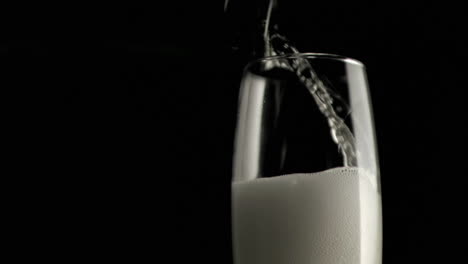 grey paper burning against champagne pouring into a glass against black background