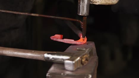 blacksmith forging metal on anvil