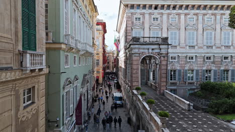 pedestrians walk on via garibaldi next to palazzo doria-tursi, drone pullback