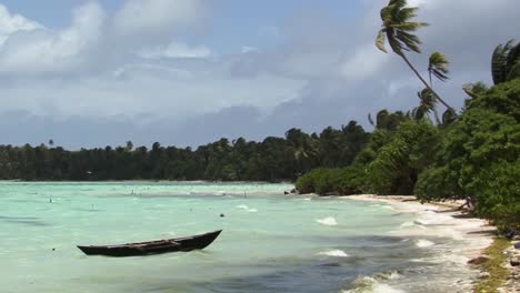 Beach,-fishing-boat-and-palm-trees-on-Fanning-Island,-Kiribati