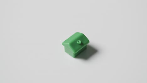 Home-Buying-Concept-With-Green-Plastic-Model-Of-House-Revolving-On-White-Background