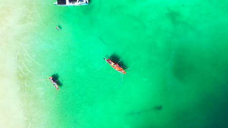 Fishing-boats-anchoring-on-green-turquoise-lagoon-near-white-sandy-beach-of-tropical-coastline-in-Vietnam