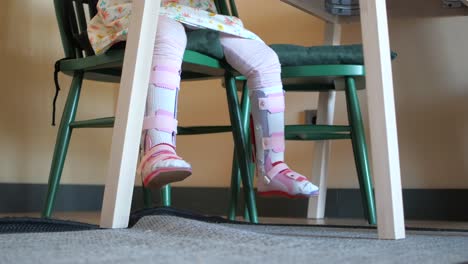 niño con soporte para las piernas sentado en la mesa