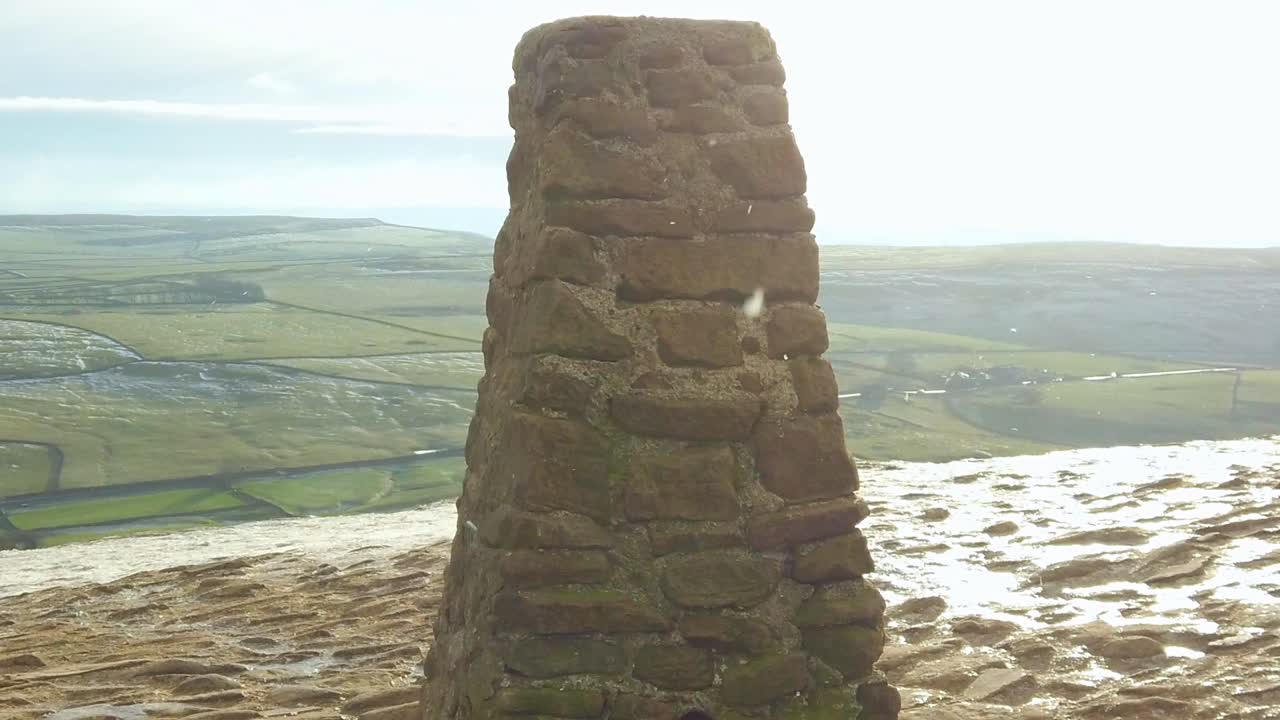 Summit of sunny, glowing mountain top slomo during snow shower