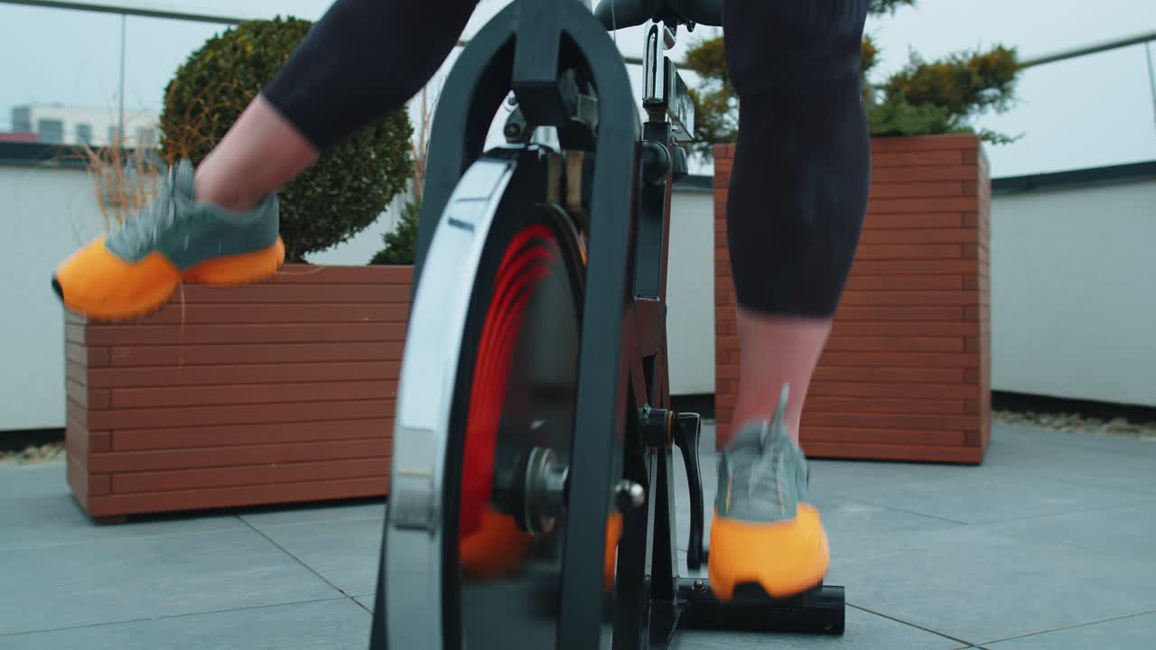 Closeup girl leg spinning pedal on stationary bike riding training workout cardio routine outdoors