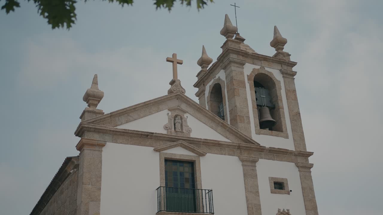 Elegant stone church with bell tower and cross viewed on a calm day