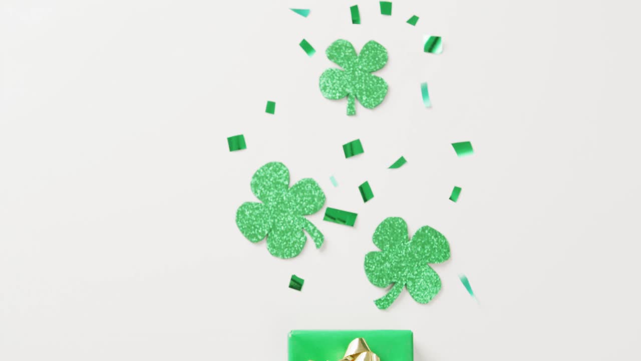 Video of st patrick's shamrock leaves and present with copy space on white background