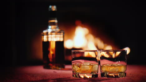 alcohol fuerte en dos vasos y una botella en el fondo un fuego arde en la chimenea