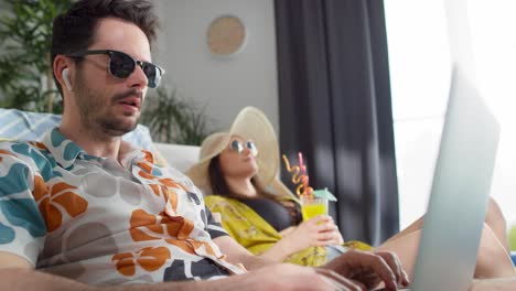 video de una pareja de vacaciones en casa con una computadora portátil