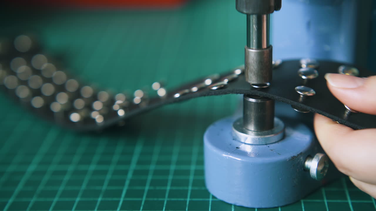 Worker fixes silver holnitens on stylish leather choker