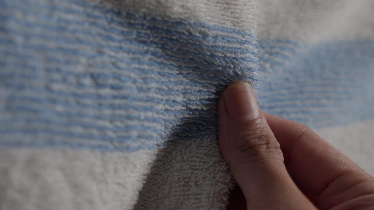 Feminine fingers feeling the texture of a blue and white towel