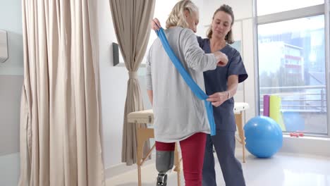 Caucasian-female-physiotherapist-and-female-senior-patient-with-prosthetic-leg-exercising