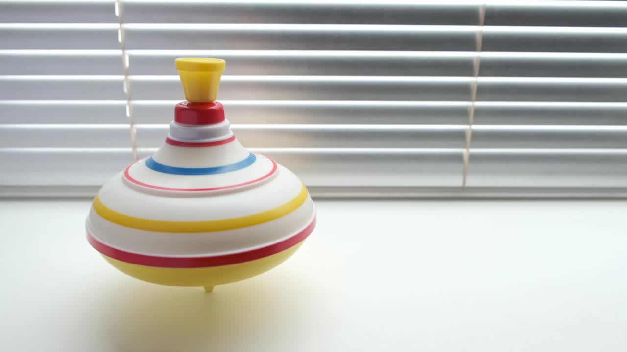 Spinning whirligig, child toy on background of blinds.