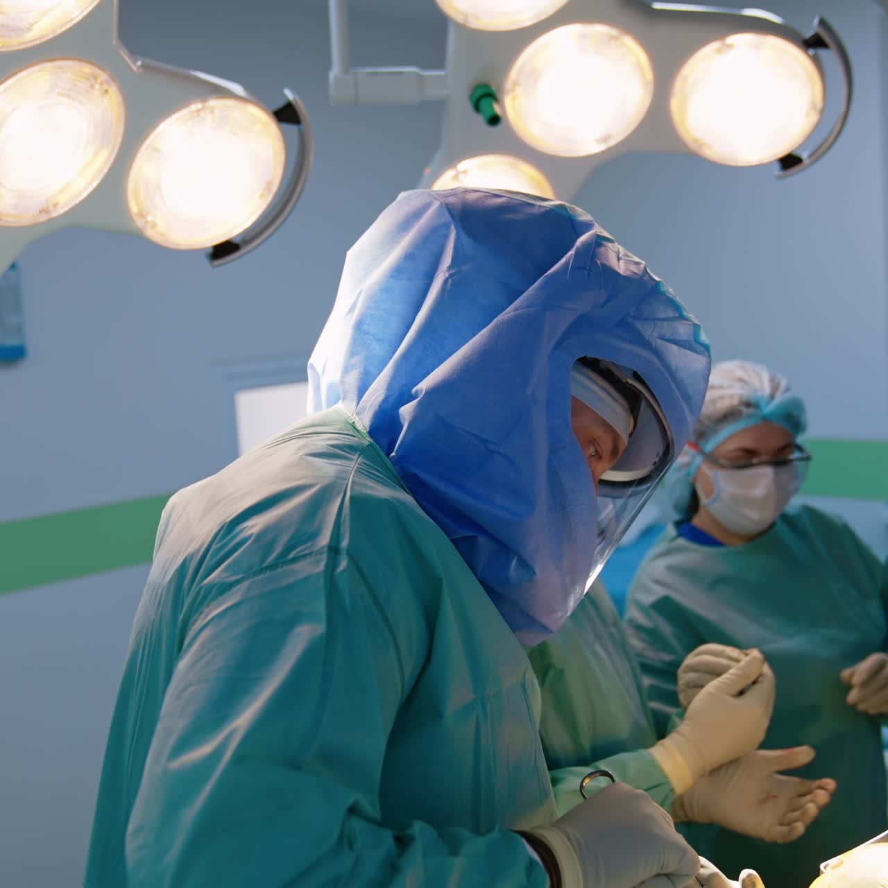 Medical team wearing protective uniform and helmets carrying out orthopedic surgery. Surgeons use metal tools
