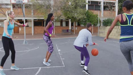 diverse female basketball team playing match, dribbling ball