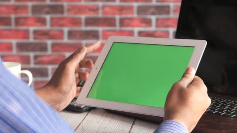 person using tablet with green screen in office