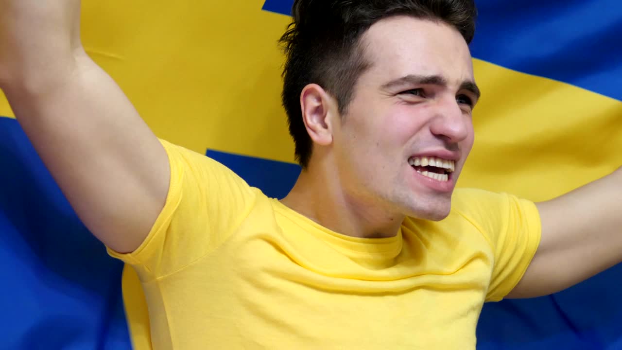 joven sueco celebrando mientras sostiene la bandera de suecia en cámara lenta