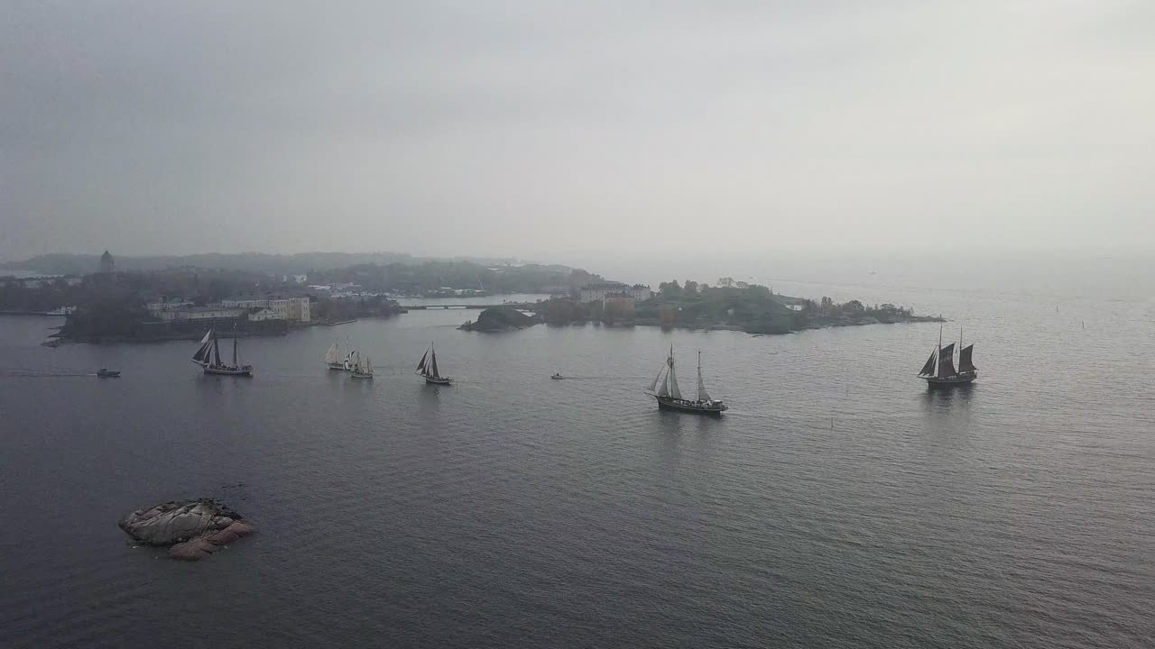 Aerial footage of tradtional wooden sailing ships sailing in front of port of Helsinki Finland