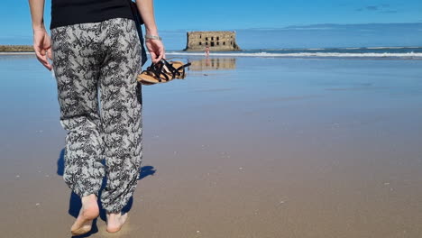 girl with long hair walks towards the beach in casa del mar, tarfaya,, marroco half body shot