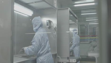 industrial painter wearing white ppe uniform spraying vehicle parts at the car service station in in an airtight cars paint booth of a garage. master is painting part of automobile in car service.