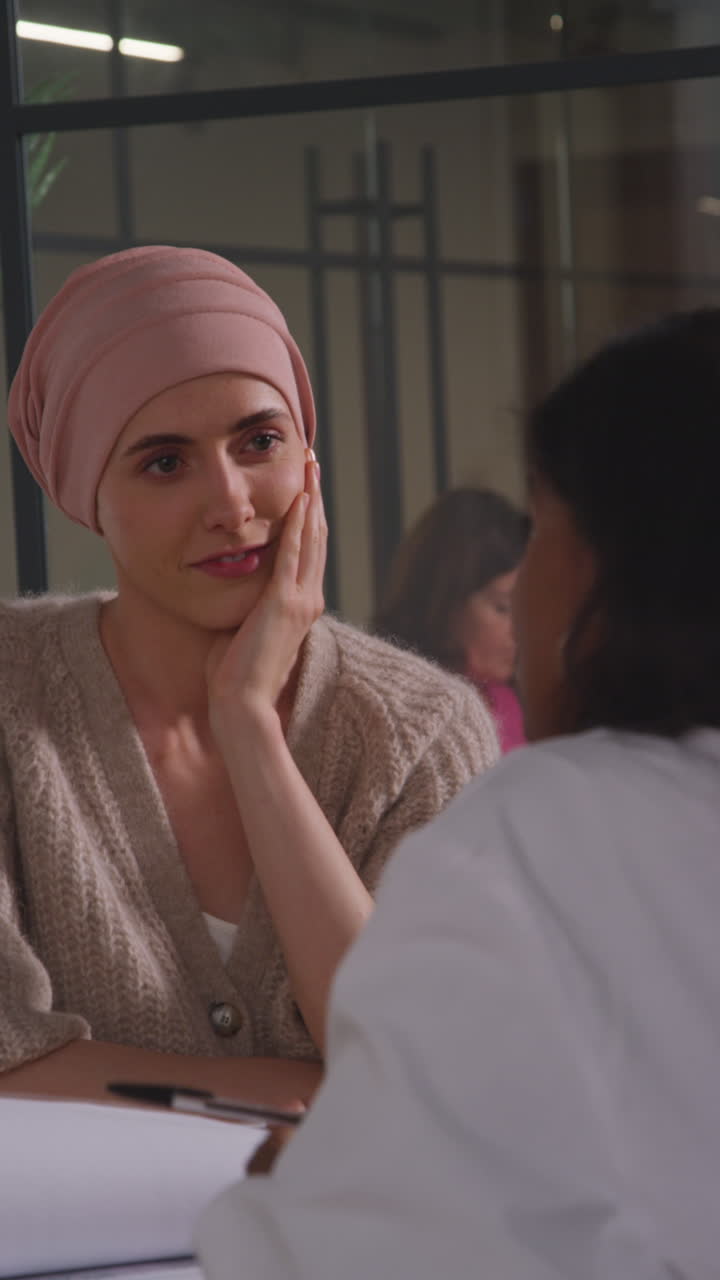 Vertical Video Of Young Woman Patient Wearing Headscarf Undergoing Chemotherapy Treatment For Breast Cancer Meeting With Oncologist Or Doctor In Hospital