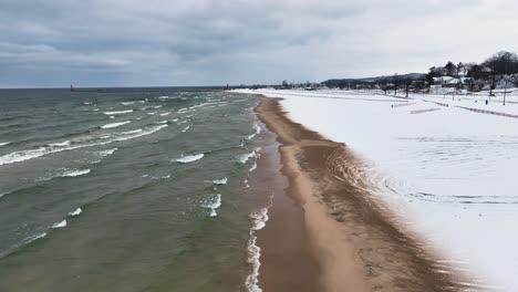 tracking the sandy shore as winter waves crash along it