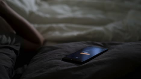 person lying in bed with phone displaying wake up alarm