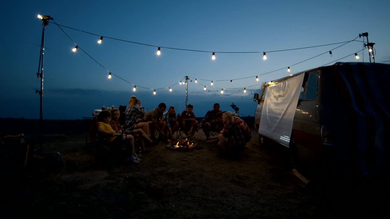 친구 들 이 황혼 에 캠프 불 에 소시지 를 고 있다