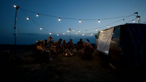 amigos fritando salchichas en el fuego del campamento en el crepúsculo