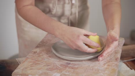 woman shaping clay plate on pottery wheel