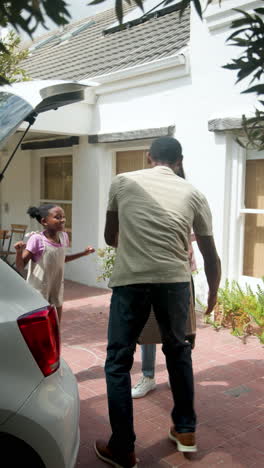 vertical video: packing car for vacation, happy family smiling and chatting outside home