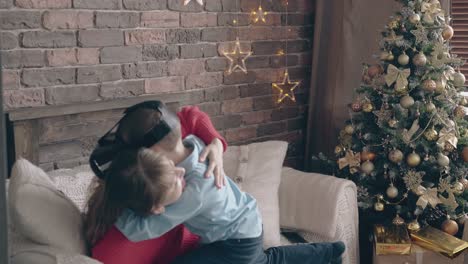 hijo con auriculares vr abraza fuerte y bonita mamá en un sofá blanco