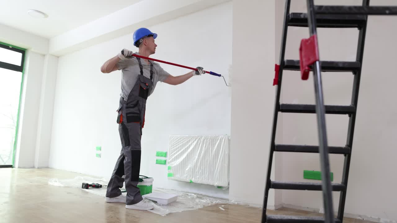 A painter painting a wall in a room