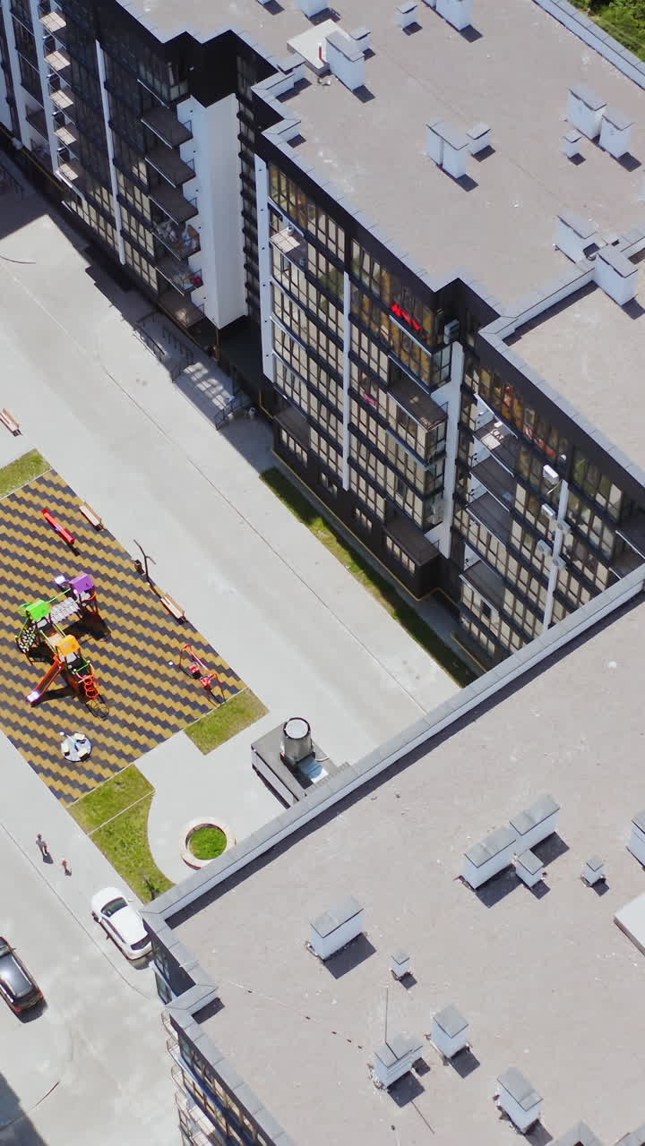 New high-rise housing apartments. Modern residential complex with playground and parking places in the city. Top aerial view. Vertical video