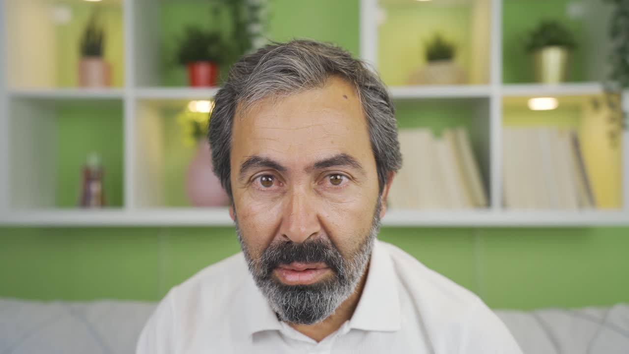 Close-up mature man warns the camera sternly and nervously.