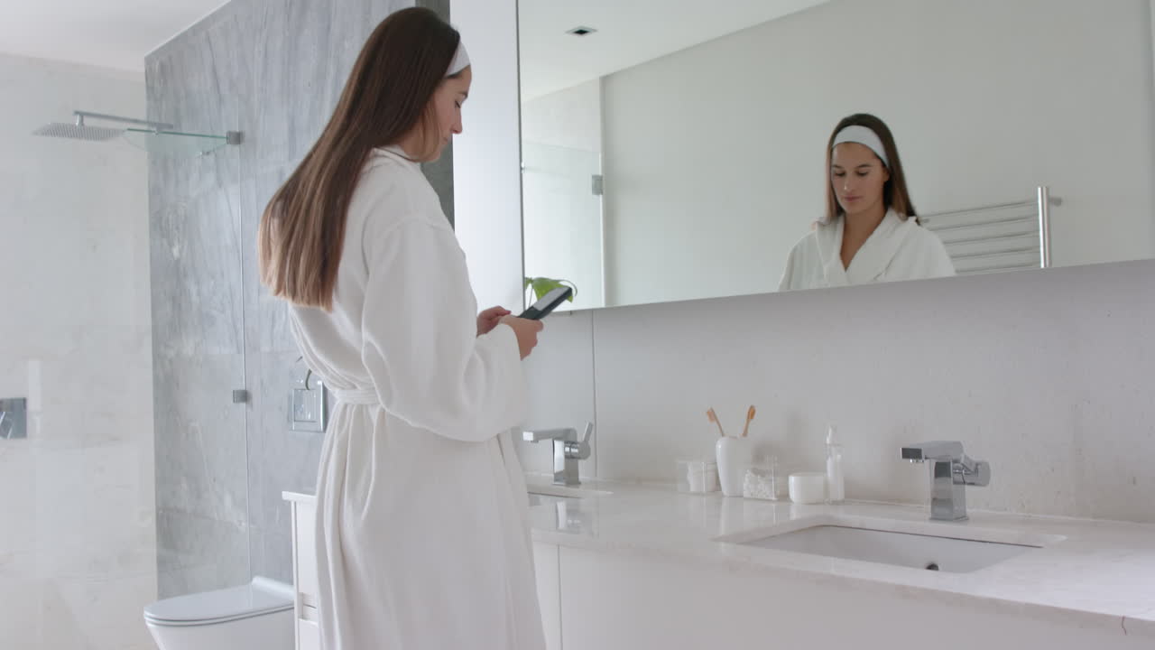 Woman in bathrobe looking in mirror, preparing for spa treatment at home
