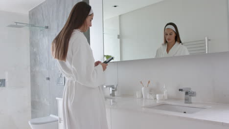 woman in bathrobe looking in mirror, preparing for spa treatment at home