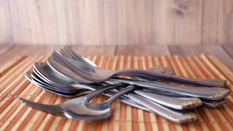 la mano recogiendo una pila de cubiertos en un placemat de bambú