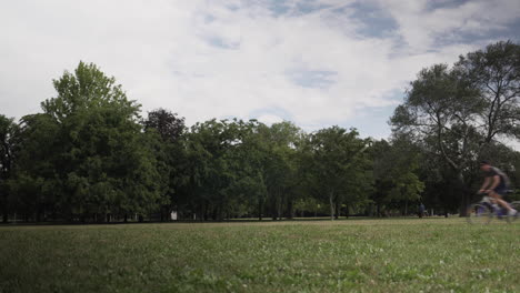 A-man-rides-his-bike-quickly-through-a-green-park-with-trees