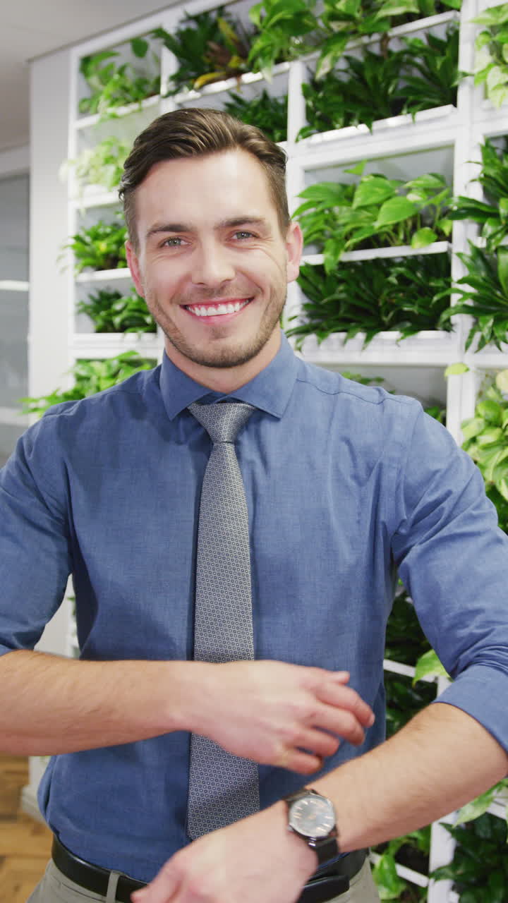 Vertical video of portrait of happy caucasian businessman smiling at office