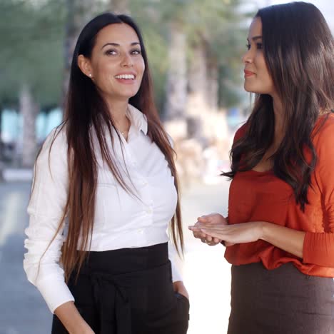 Two-natural-young-woman-standing-talking