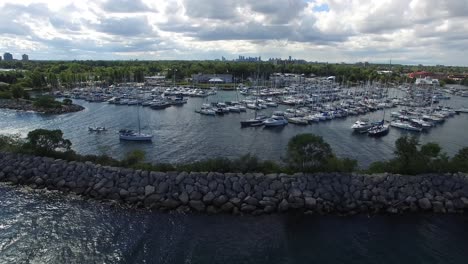 Bright-partially-cloudy-day-viewed-from-drone-over-nice-lush-coastal-marina