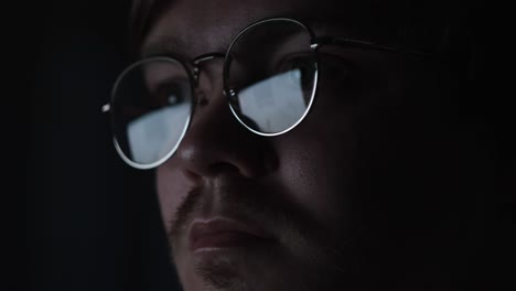 hombre concentrado en una computadora en la oscuridad