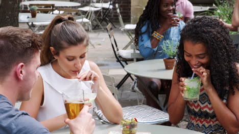 group of friends meeting for drinks at outdoor tables in restaurant