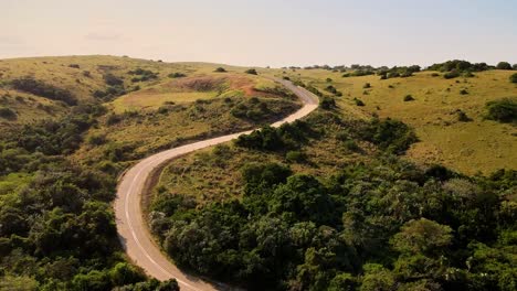 Pintoresca-Carretera-Asfaltada-Y-Sinuosa-En-La-Zona-Rural-De-Transkei,-Sudáfrica,-Que-Asciende-Una-Colina-Con-Impresionantes-Vistas-Del-Océano-A-Lo-Lejos