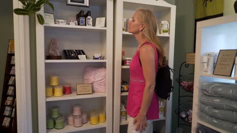 beautiful woman peruses spa merchandise like soaps, oils and robes