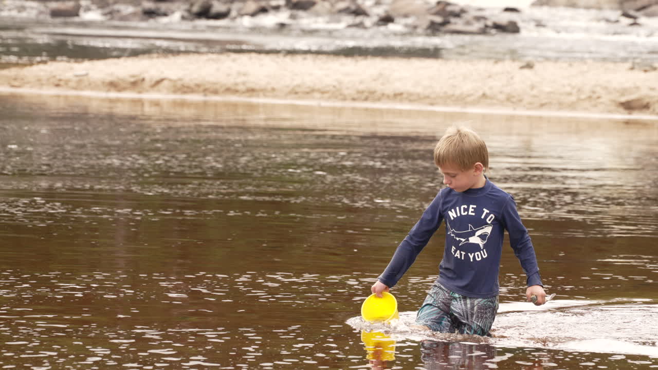호수에서 양동이에 물을 모으는 어린 소년, 느린 동작